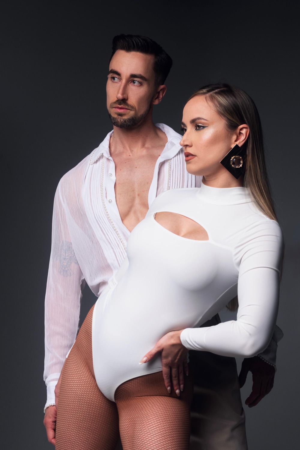 Borja y Estefanía Martínez, vestidos de blanco, posando en estudio sobre fondo gris oscuro